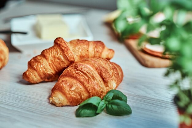 Foto de close-up de um croissant com presunto e queijo na placa de madeira.
