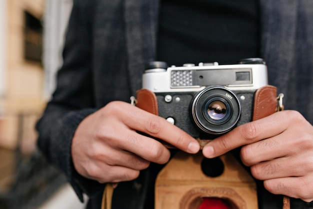 Foto de close-up de um homem com pele morena em pé na rua após a sessão de fotos. retrato ao ar livre de mãos masculinas segurando uma câmera.