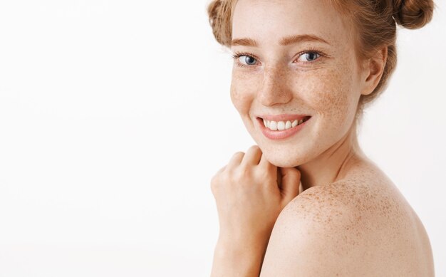 Foto de close-up de uma fêmea de gengibre bonita, macia e feminina, de pé, nua, virada de perfil com um sorriso fofo e feliz tomando banho, desfrutando e relaxando durante o procedimento cosmetológico