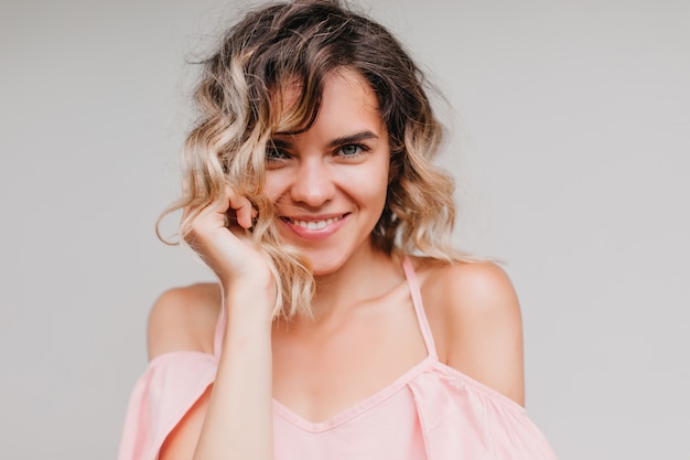 Foto de close-up de uma garota incrível com pele bronzeada rindo. retrato de feliz senhora caucasiana de vestido rosa.