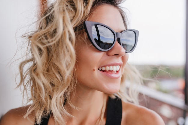 Foto de close-up de uma jovem magnífica com cabelo loiro curto. retrato de uma deslumbrante garota bronzeada que expressa verdadeiras emoções positivas.