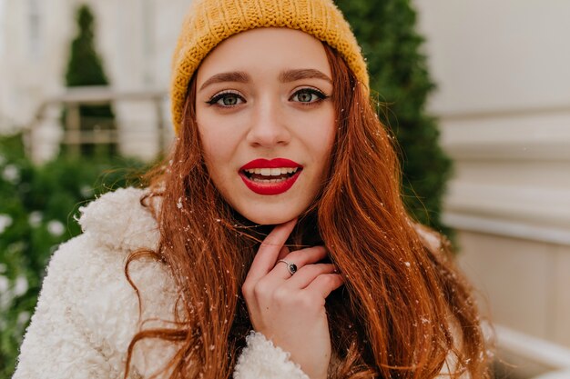 Foto de close-up de uma mulher despreocupada com longos cabelos ruivos. Foto ao ar livre da senhora jocund posando no inverno.