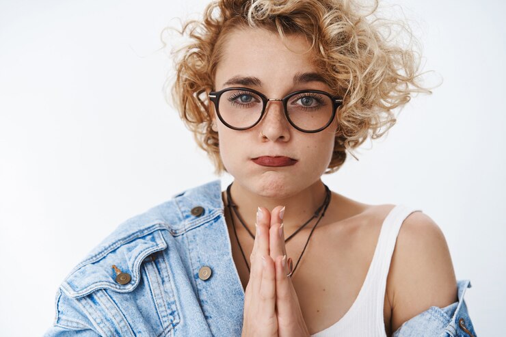 Foto grátis foto de close-up de uma mulher fofa fazendo beicinho implorando por favor, fazendo cara de boba por estar precisando de mãos dadas para orar enquanto pede desculpas ou emprestar dinheiro em pé sombrio com olhar esperançoso na frente