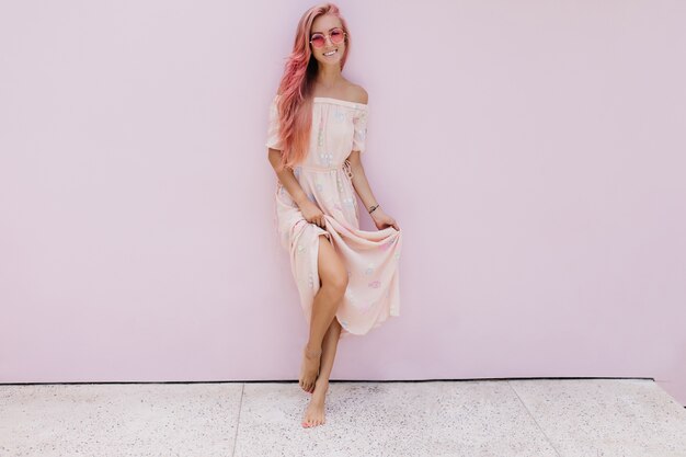 Foto de corpo inteiro de rir mulher magro com cabelo rosa expressando felicidade.