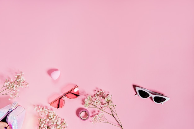 Foto de dois pares de óculos de sol bonitos na parede rosa com flores