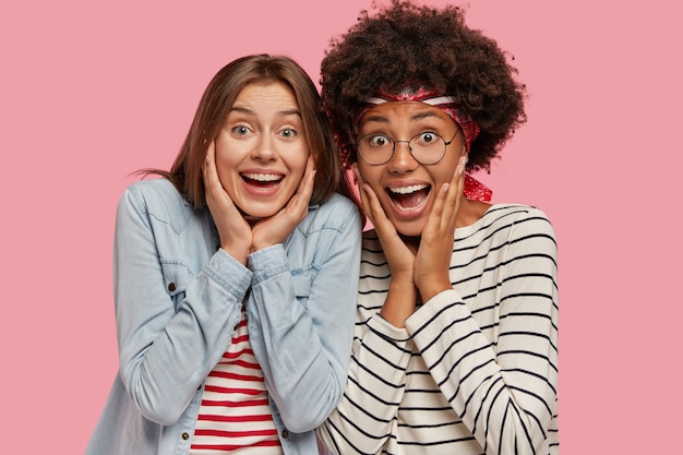 Foto de duas mulheres muito animadas e entusiasmadas exclamarem de felicidade, mantenha as mãos nas bochechas