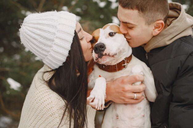 Foto de estilo de vida de casal em um bosque nevado com cachorro