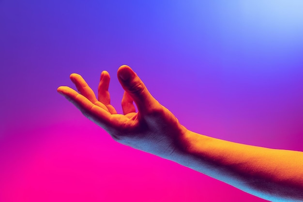 Foto de estúdio da mão masculina isolada sobre fundo rosa gradiente azul na luz neon