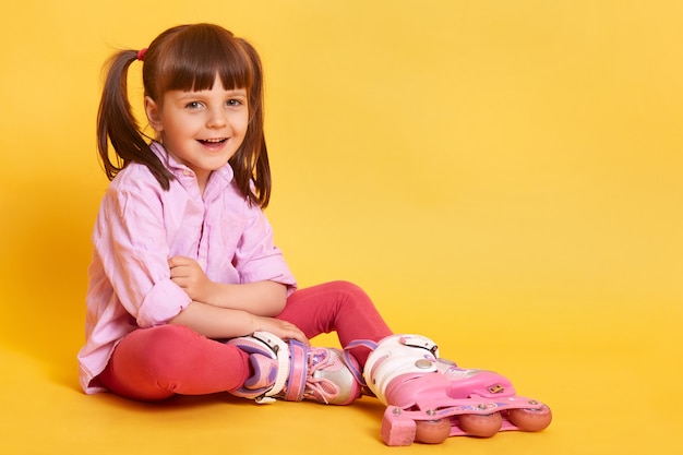 Foto de estúdio da menina sorridente feliz sentada no chão