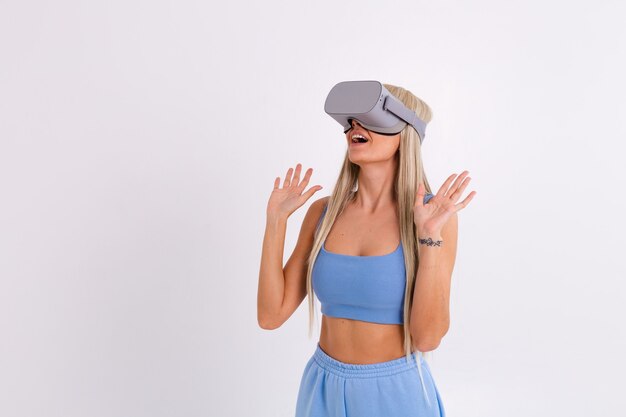 Foto de estúdio de uma jovem mulher atraente em um terno elegante azul quente usando óculos de realidade virtual em um branco