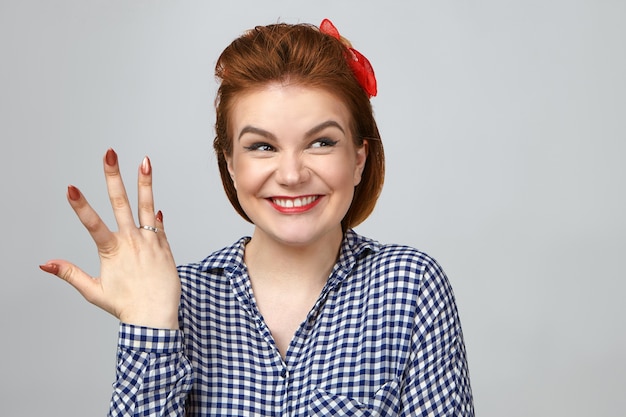 Foto de estúdio de uma jovem ruiva em êxtase, sorrindo amplamente, ficando animada depois que seu namorado a pediu em casamento. garota muito feliz mostrando o anel de noivado no dedo, feliz com o pedido de casamento