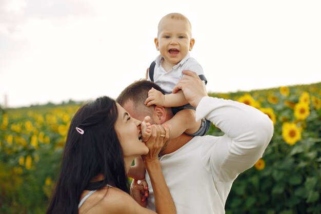 Foto de família feliz. Pais e filha. Família unida no campo de girassol. Homem de camisa branca.
