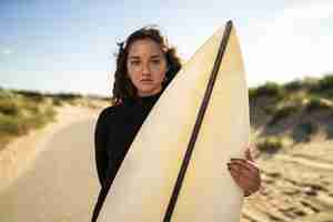 Foto grátis foto de foco raso de uma mulher atraente segurando uma prancha de surfe no meio de uma estrada na espanha