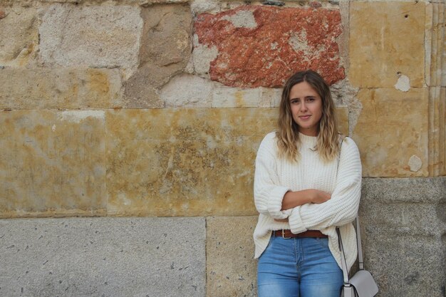 Foto de foco raso de uma mulher loira atraente com um suéter branco posando para a câmera