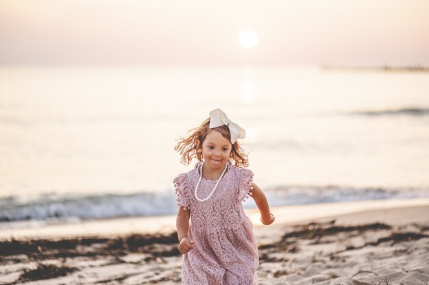 Foto de foco raso de uma pequena menina loira na praia