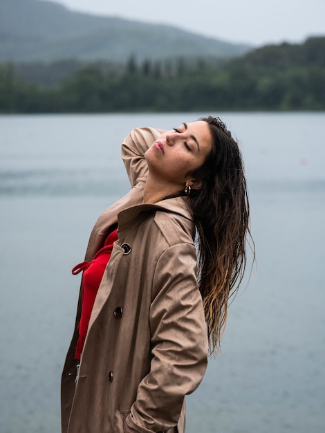 Foto de foco raso vertical de uma mulher branca com cabelo molhado respirando ar fresco na praia