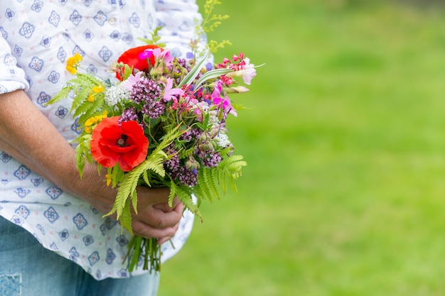 Foto de foco seletivo de alguém segurando um buquê de flores diferentes ao ar livre durante o dia