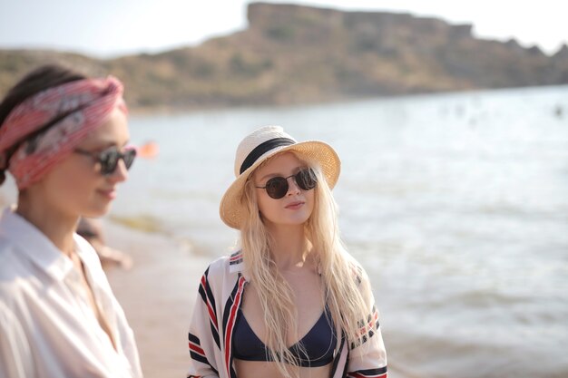 Foto de foco seletivo de duas mulheres de óculos na praia