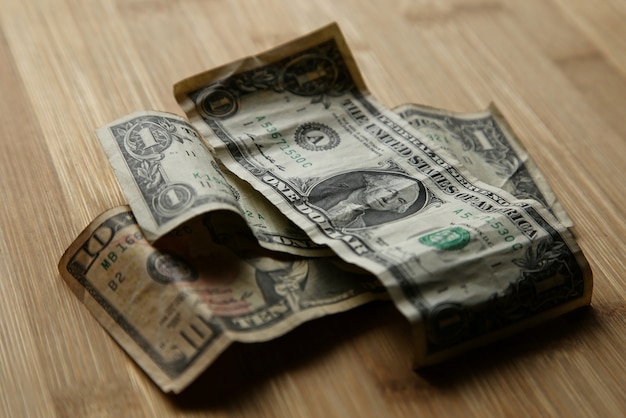 Foto de foco seletivo de notas de dólar uma em cima da outra em uma superfície de madeira
