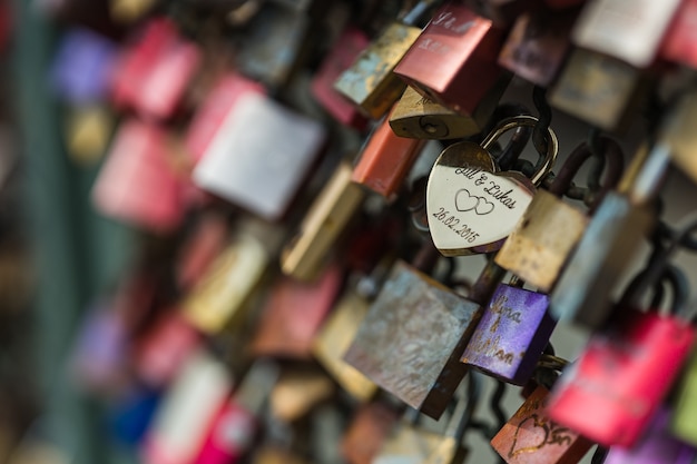 Foto de foco seletivo de um cadeado de amor em uma cerca