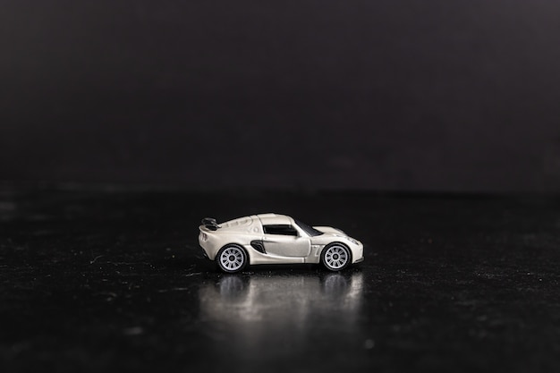 Foto de foco seletivo de um carro esporte de brinquedo branco em uma superfície preta