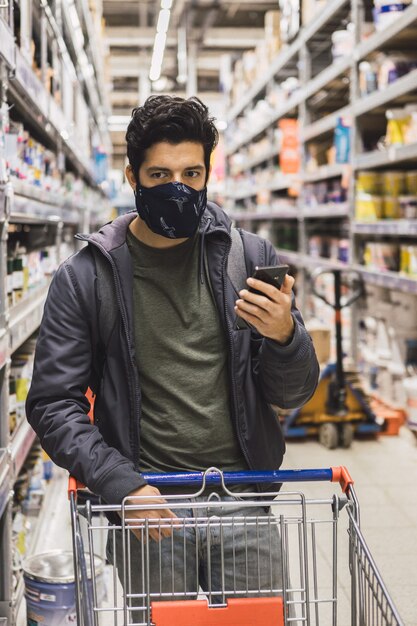 Foto de foco seletivo de um jovem do sexo masculino com uma máscara examinando o que comprar - conceito de novo normal