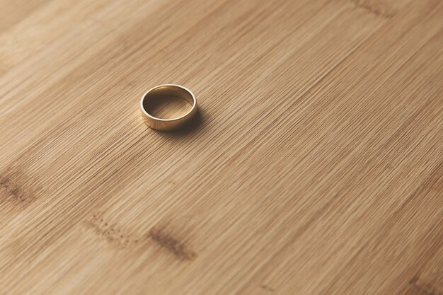 Foto de foco seletivo de uma aliança de ouro em uma superfície de madeira