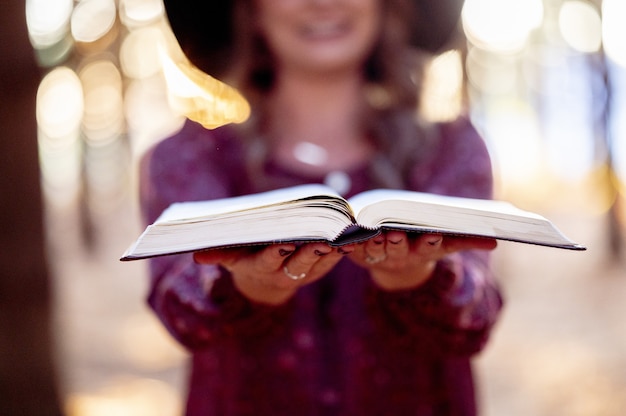 Foto grátis foto de foco seletivo de uma mulher segurando um livro aberto