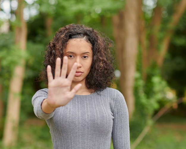 Foto de foco seletivo de uma mulher séria e determinada mostrando o sinal de pare