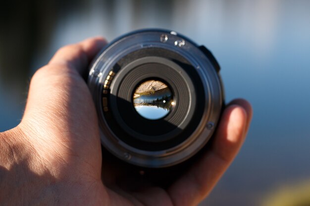 Foto de foco seletivo de uma pessoa segurando uma lente de câmera