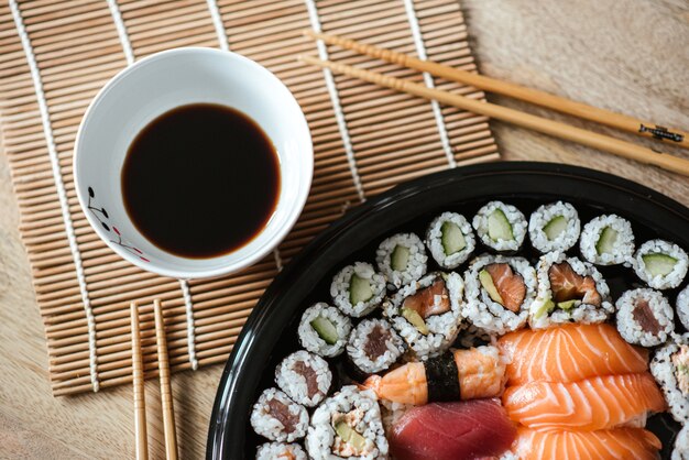 Foto de foco seletivo dos deliciosos rolos de sushi servidos em um prato preto redondo