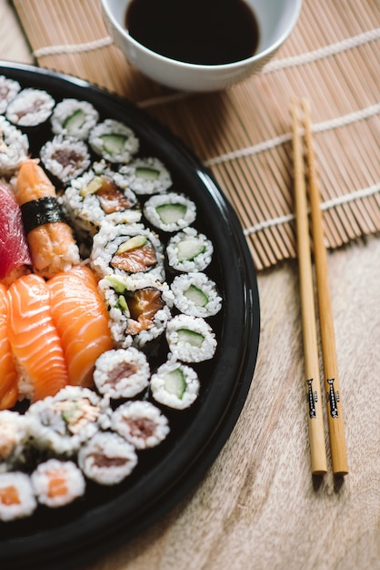 Foto de foco seletivo dos deliciosos rolos de sushi servidos em um prato preto redondo