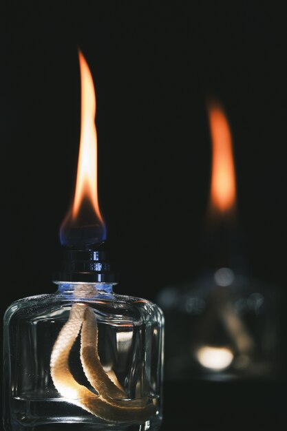 Foto de foco seletivo vertical de dois isqueiros a álcool isolados em um fundo preto