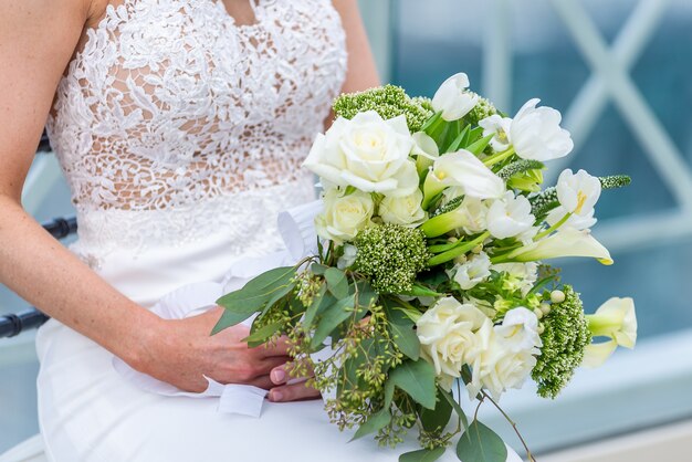 Foto de foco superficial de uma noiva em um vestido de noiva segurando um buquê de flores