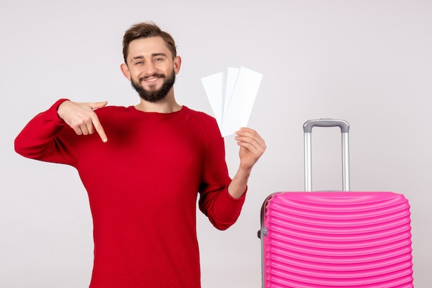 Foto de frente, jovem do sexo masculino com bolsa rosa e bilhetes na parede branca viagem voo colorido, viagem turística, férias, emoções, foto