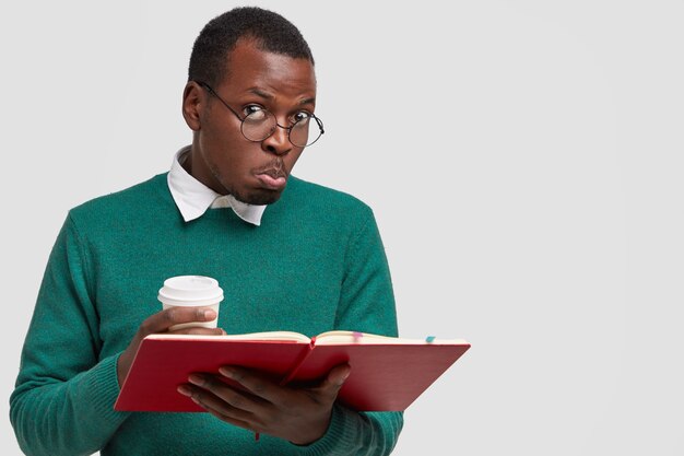 Foto de homem negro confuso franze os lábios, tem expressão facial intrigada, lê informações necessárias para exame