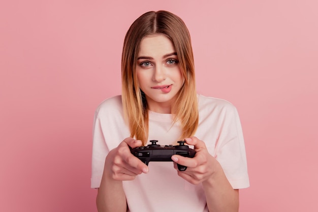 Foto de jovem mulher com lábios mordidos viciada em joystick de perdedor de videogame isolado em um fundo de cor rosa Foto Premium