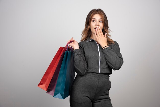 Foto de jovem segurando sacolas de compras.