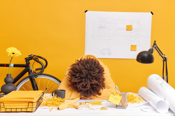 Foto grátis foto de mulher exausta e cansada inclina-se na mesa trabalhou o dia todo no projeto arquitetônico quer dormir poses na área de trabalho com adesivos de esboços de papel enrolado. conceito de ocupação de prazo de pessoas.