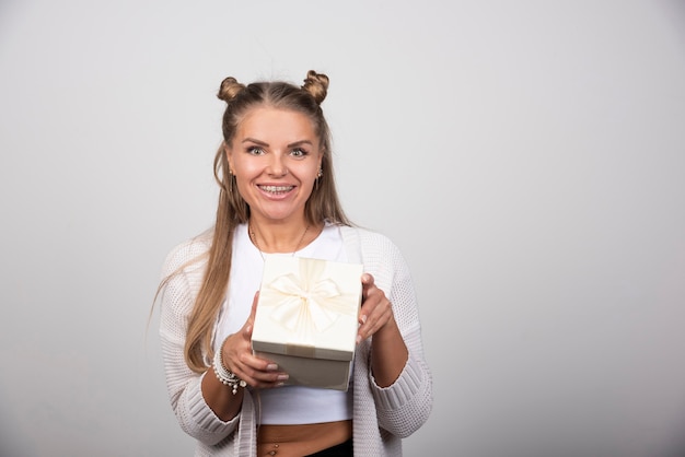 Foto de mulher sorridente segurando uma caixa de presente.