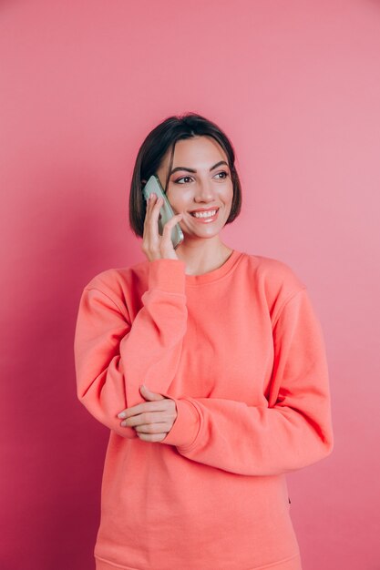 Foto de mulher sorrindo enquanto fala em smartphone isolada sobre fundo rosa