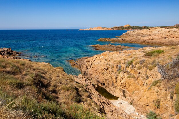 Foto de paisagem de colinas rochosas em um oceano azul aberto com um céu azul claro