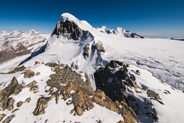 Foto grátis foto de tirar o fôlego das montanhas rochosas cobertas de neve sob um céu azul