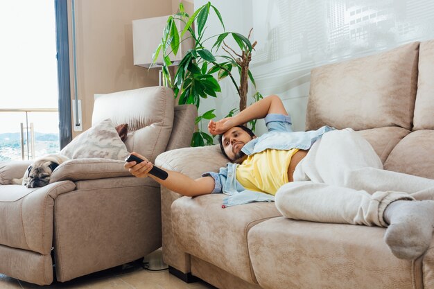 Foto de um belo homem hispânico deitado em um sofá e assistindo TV