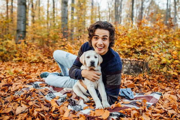 Foto de um homem bonito e seu cachorro passam um tempo na floresta de outono.