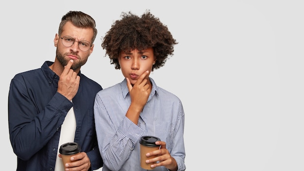 Foto de um jovem casal multiétnico pensativo e perplexo segurando o queixo