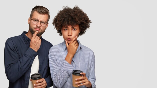 Foto de um jovem casal multiétnico pensativo e perplexo segurando o queixo