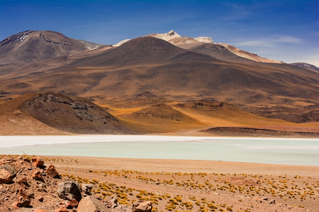 Foto de um lago contra montanhas marrons hipnotizantes sob o grande céu