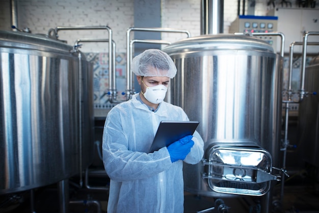 Foto de um tecnólogo caucasiano altamente concentrado e focado controlando a produção em uma fábrica de processamento de alimentos ou indústria farmacêutica
