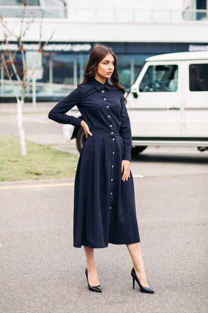 Foto de uma bela mulher caucasiana com cabelo castanho ondulado londres e rosto bonito em um vestido preto e sapatos pretos do lado de fora